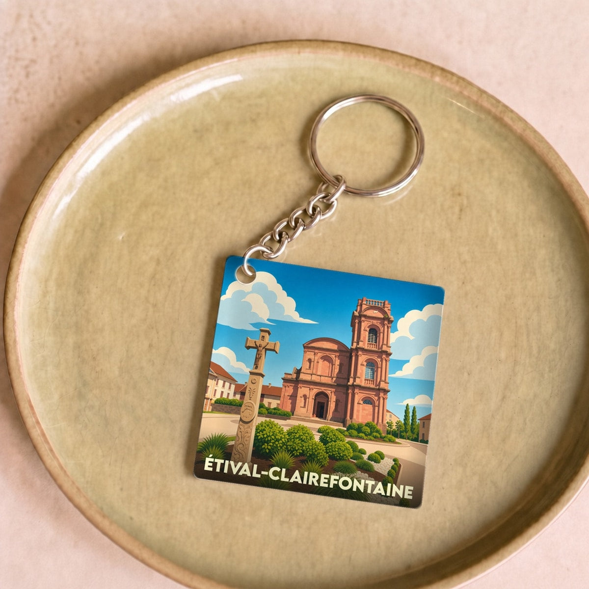 Porte-clés souvenir de la ville d'Étival-Clairefontaine avec une illustration stylisée de son église et de sa croix monumentale.