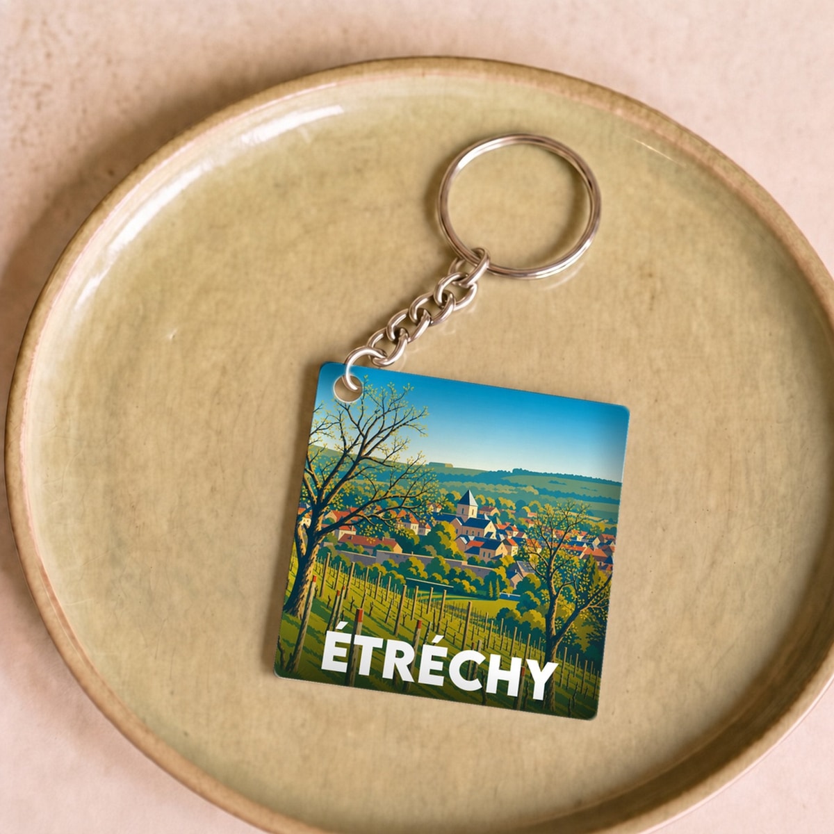 Porte-clés souvenir de la ville d'Étréchy avec une illustration paysagère stylisée.