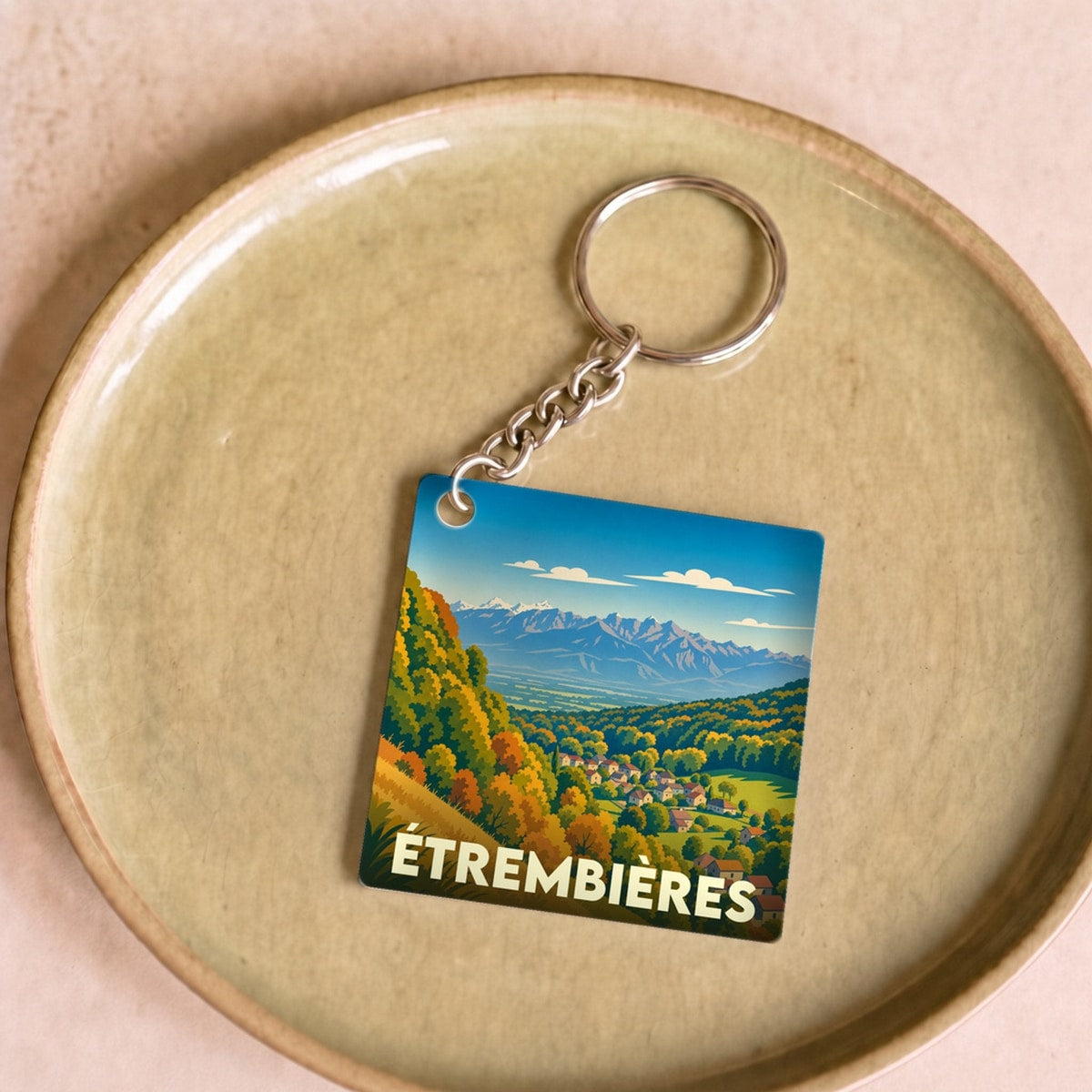 Porte-clés souvenir de la ville d'Étrembières avec une illustration stylisée de paysages montagneux.