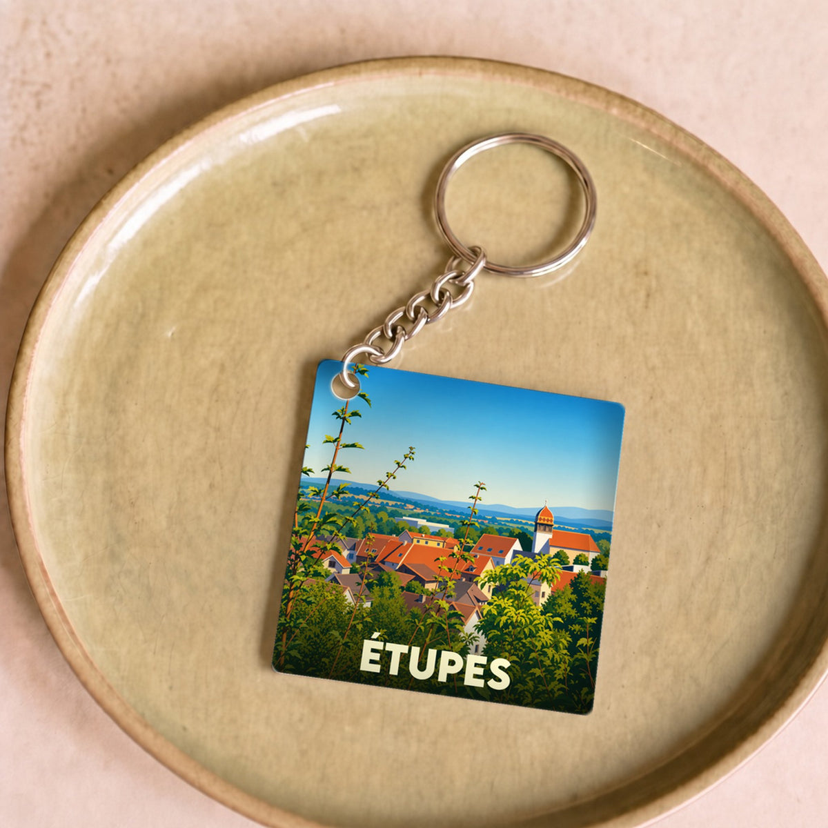 Porte-clés souvenir de la ville d'Étupes avec une illustration stylisée du paysage urbain.