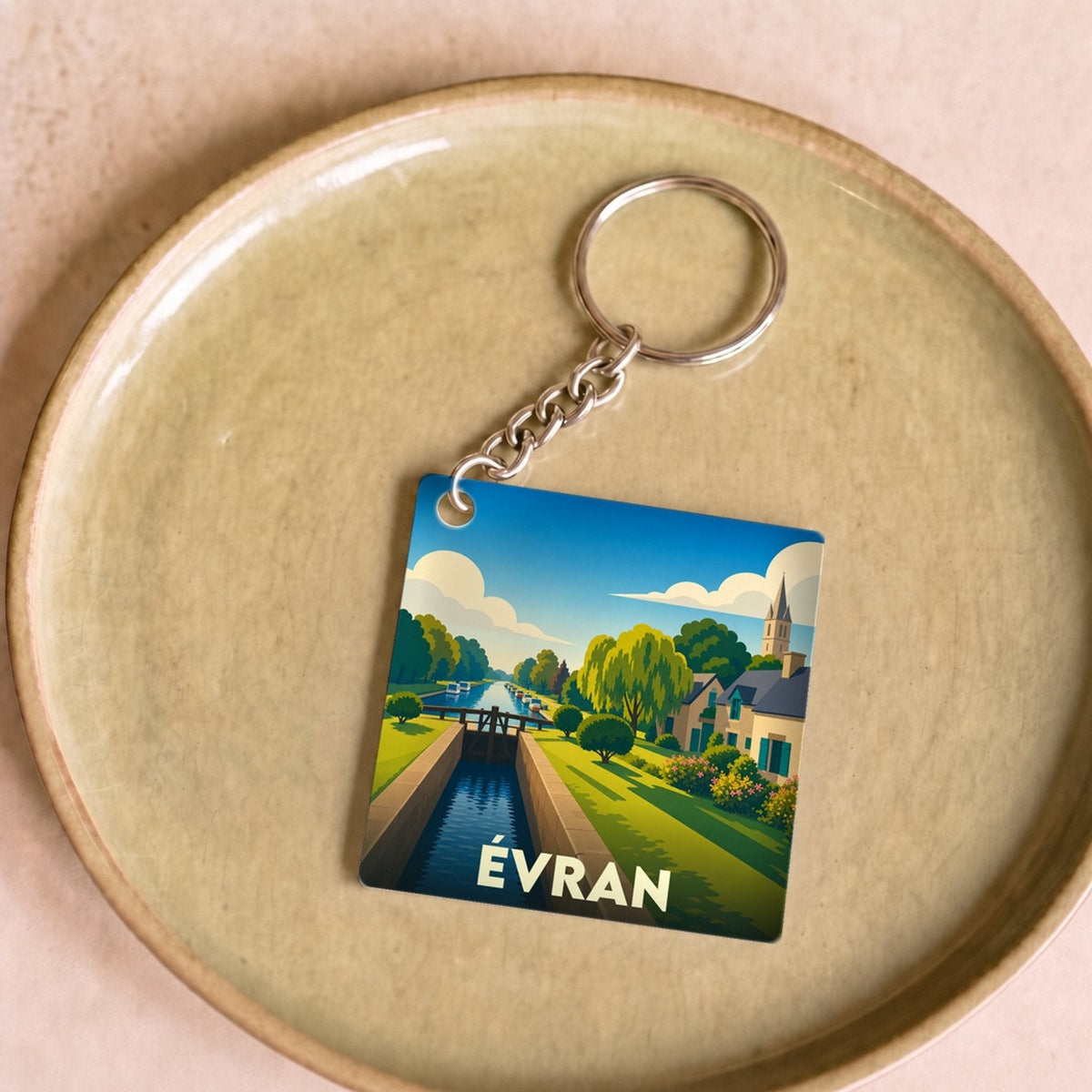 Porte-clés souvenir de la ville de Évran avec une illustration stylisée d'un canal et d'une écluse.