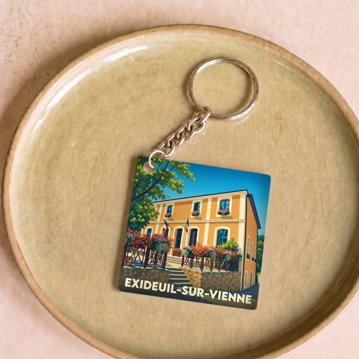 Porte-clés souvenir de la ville d'Exideuil-sur-Vienne avec une illustration stylisée.