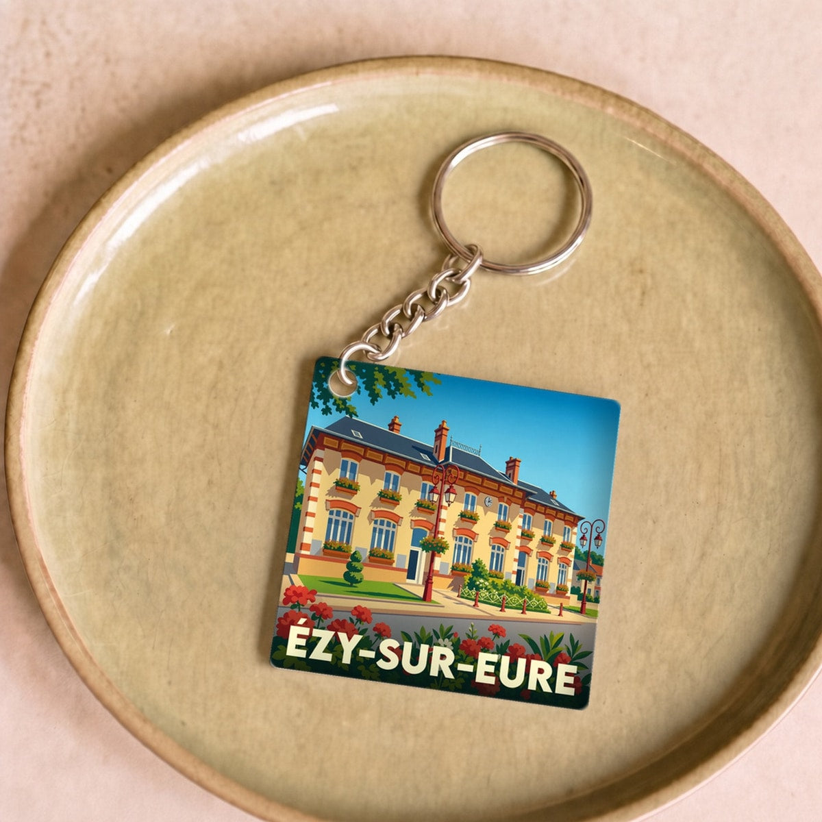 Porte-clés souvenir de la ville d'Ézy-sur-Eure avec une illustration stylisée de sa mairie.