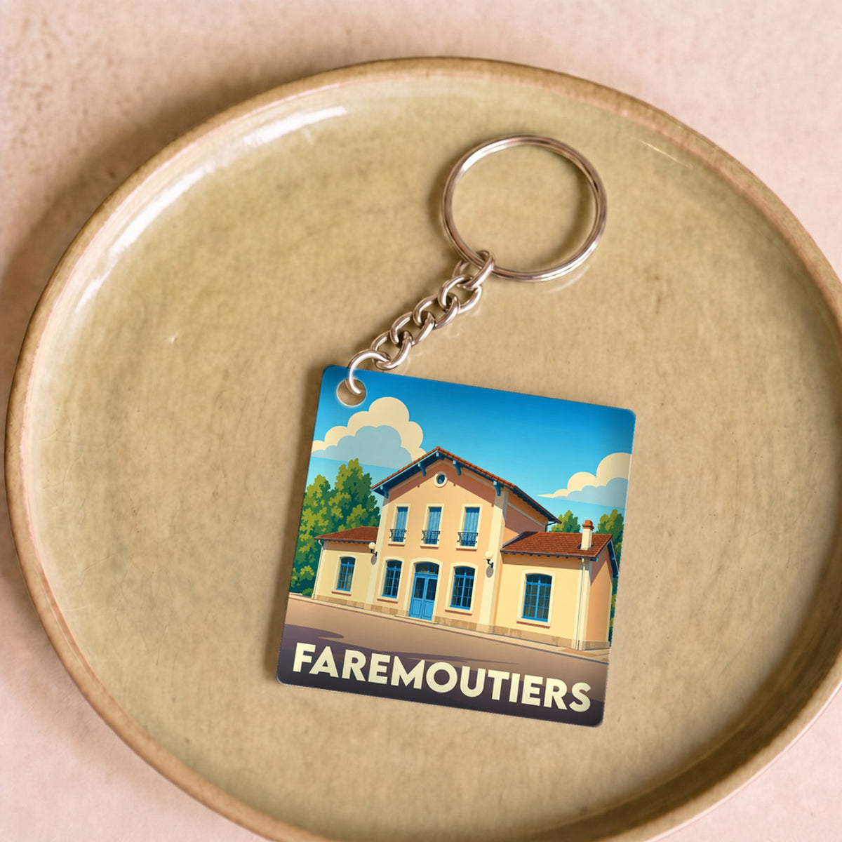 Porte-clés souvenir de la ville de Faremoutiers avec une illustration stylisée.