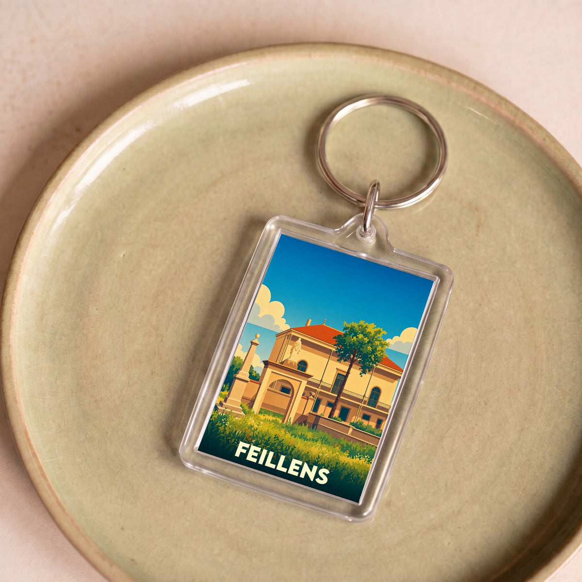 Porte-clés souvenir de la ville de Feillens avec une illustration stylisée d'un monument historique.
