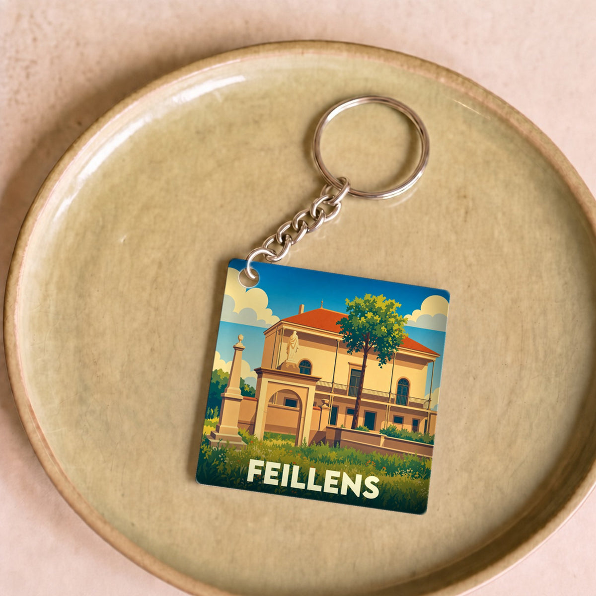 Porte-clés souvenir de la ville de Feillens avec une illustration stylisée d'un monument historique.