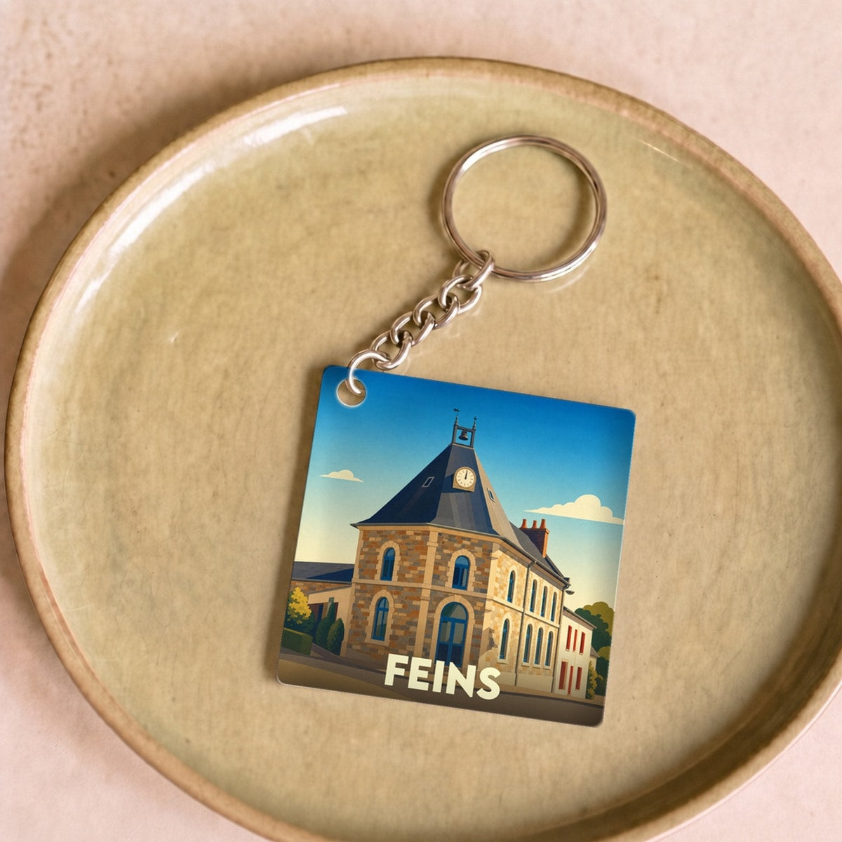 Porte-clés souvenir de la ville de Feins avec une illustration stylisée de son église.