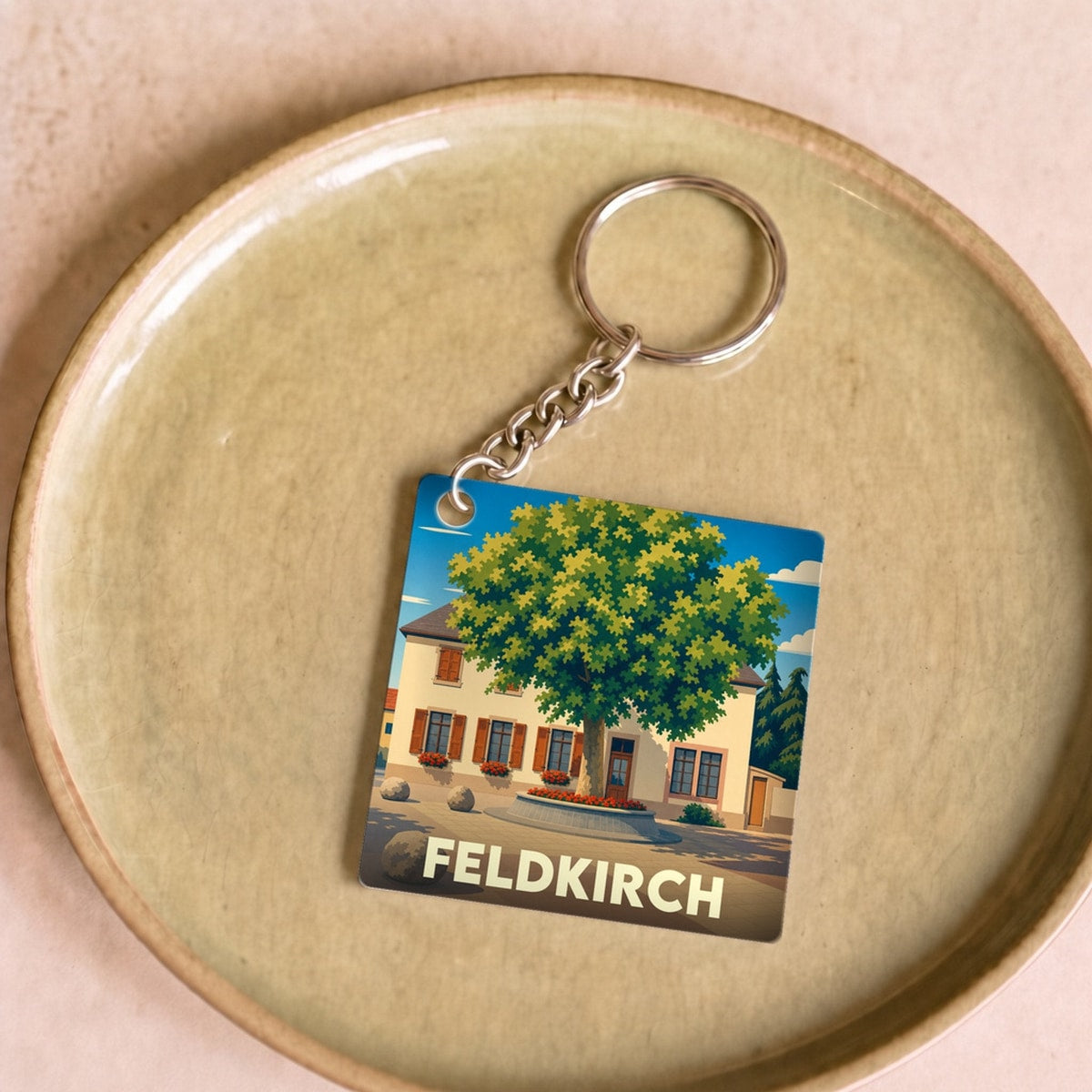 Porte-clés souvenir de la ville de Feldkirch avec une illustration stylisée d'une place arborée.