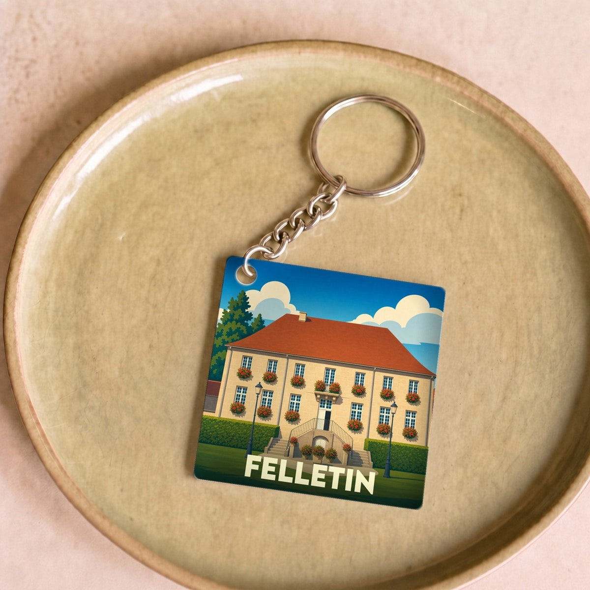 Porte-clés souvenir de la ville de Felletin avec une illustration stylisée d'un bâtiment fleuri.