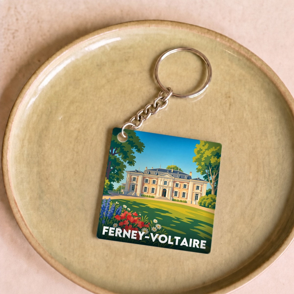 Porte-clés souvenir de la ville de Ferney-Voltaire avec une illustration stylisée.