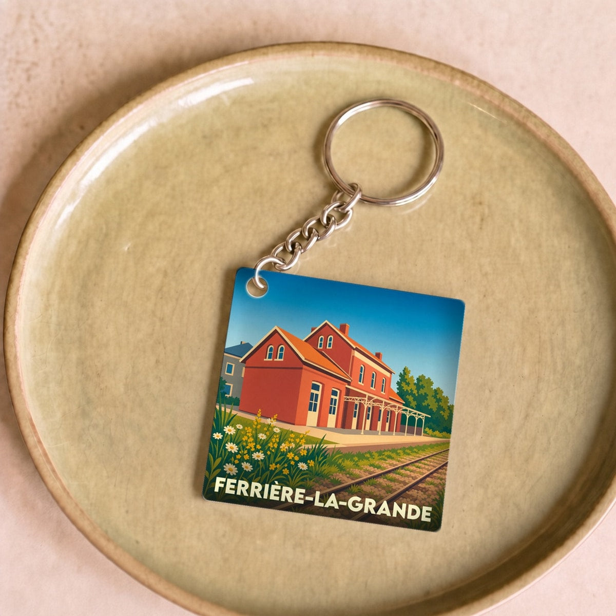Porte-clés souvenir de la ville de Ferrière-la-Grande avec une illustration stylisée de sa gare.