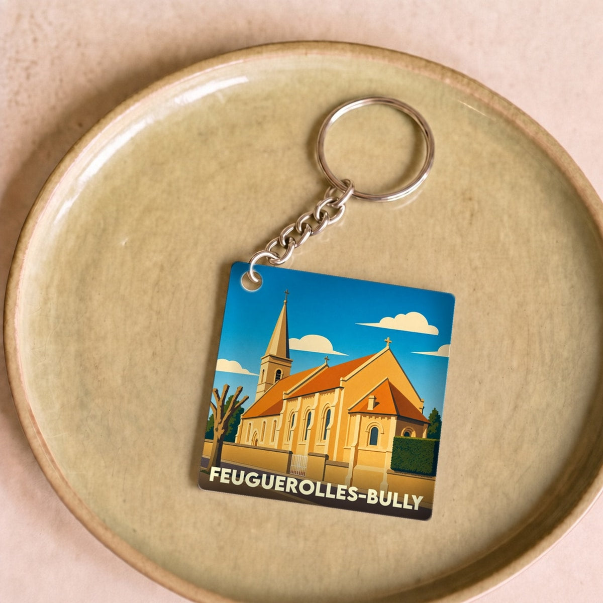 Porte-clés souvenir de la ville de Feuguerolles-Bully avec une illustration stylisée de son église.