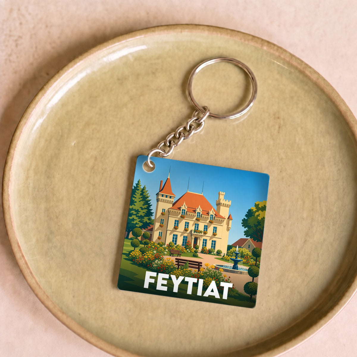 Porte-clés souvenir de la ville de Feytiat avec une illustration stylisée d'un château fleuri.
