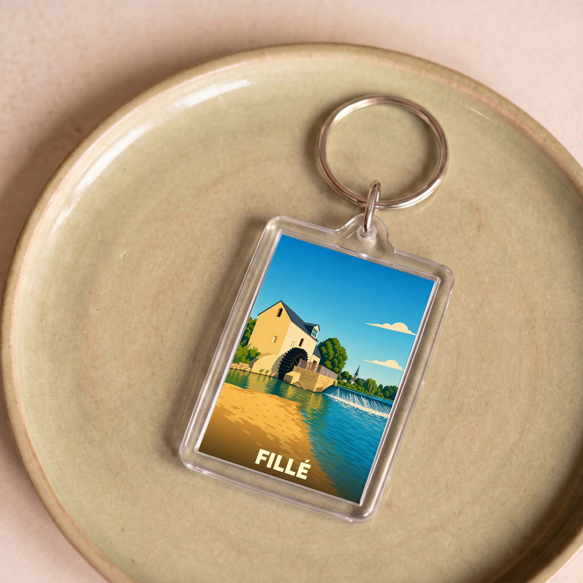 Porte-clés souvenir de la ville de Fillé avec une illustration stylisée de son moulin au bord de l'eau.