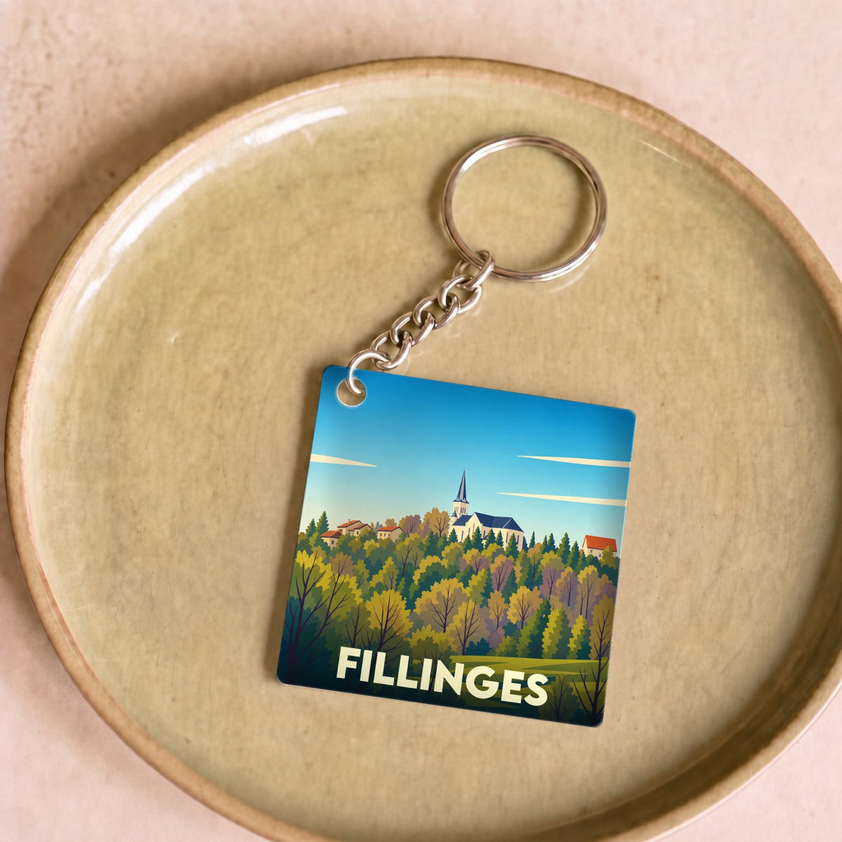 Porte-clés souvenir de la ville de Fillinges avec une illustration stylisée de son paysage.
