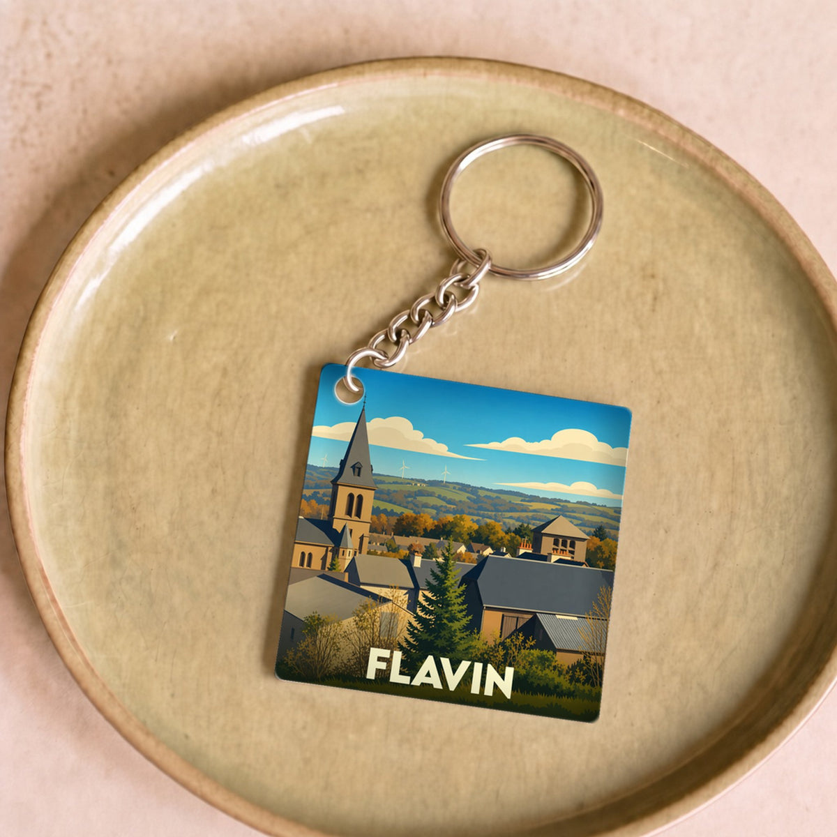 Porte-clés souvenir de la ville de Flavin avec une illustration stylisée de son église et de ses paysages.