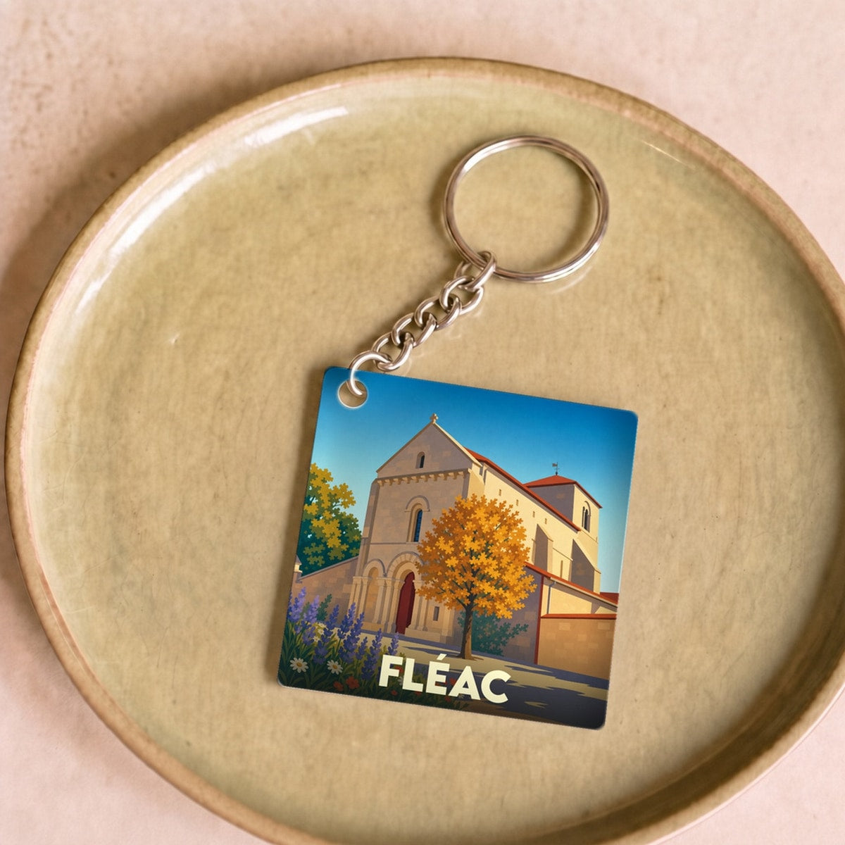 Porte-clés souvenir de la ville de Fléac avec une illustration stylisée de son église.