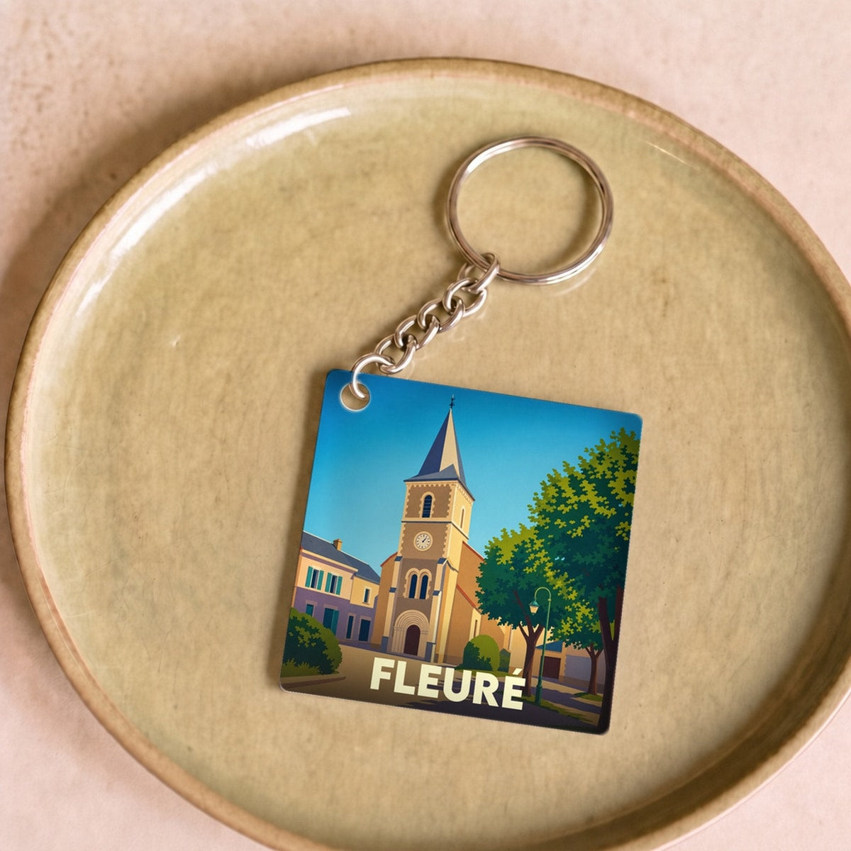 Porte-clés souvenir de la ville de Fleuré avec une illustration stylisée de son église.