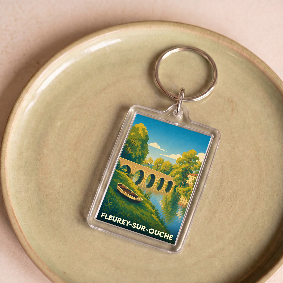Porte-clés souvenir de la ville de Fleurey-sur-Ouche avec une illustration stylisée d'un pont et d'une rivière.