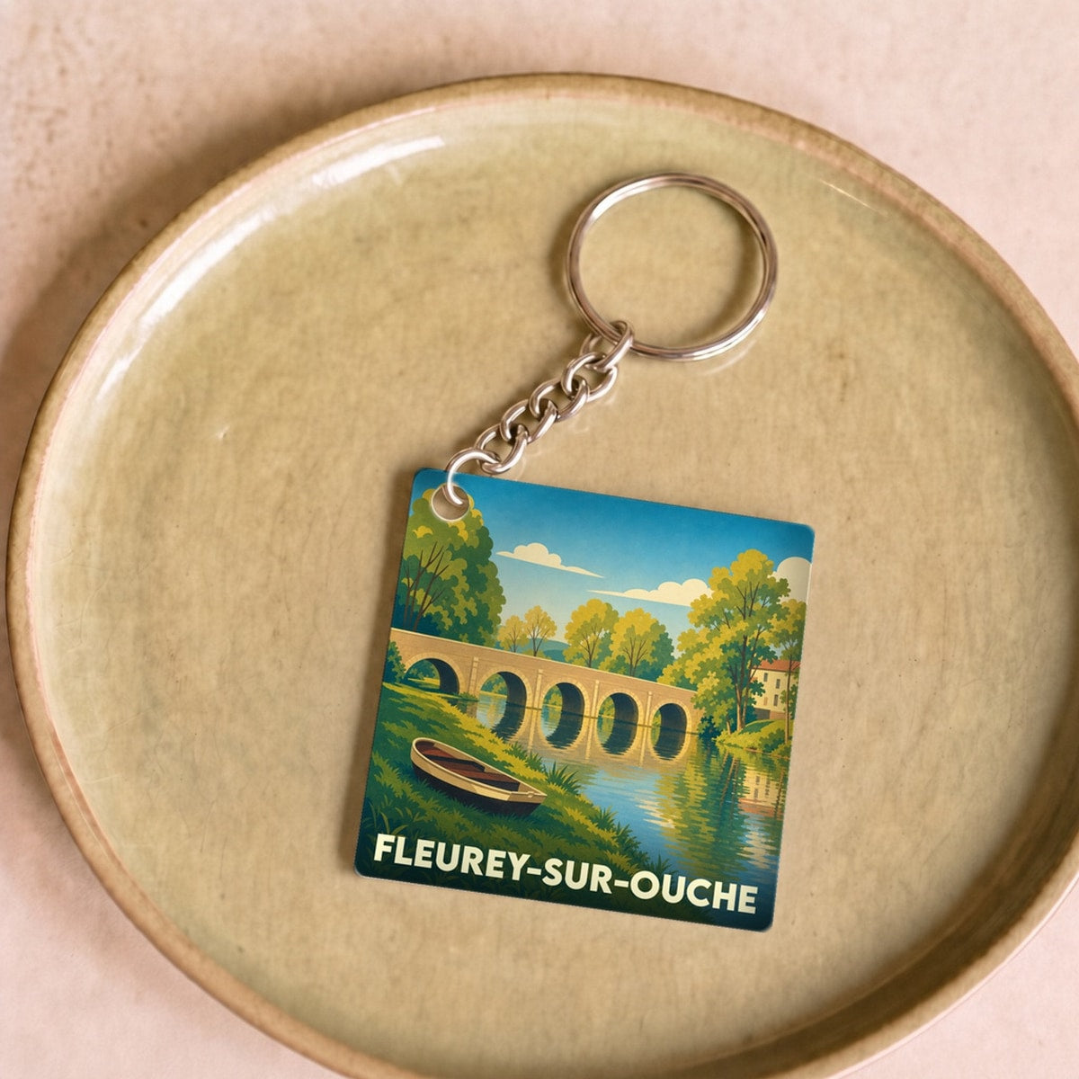 Porte-clés souvenir de la ville de Fleurey-sur-Ouche avec une illustration stylisée d'un pont et d'une rivière.