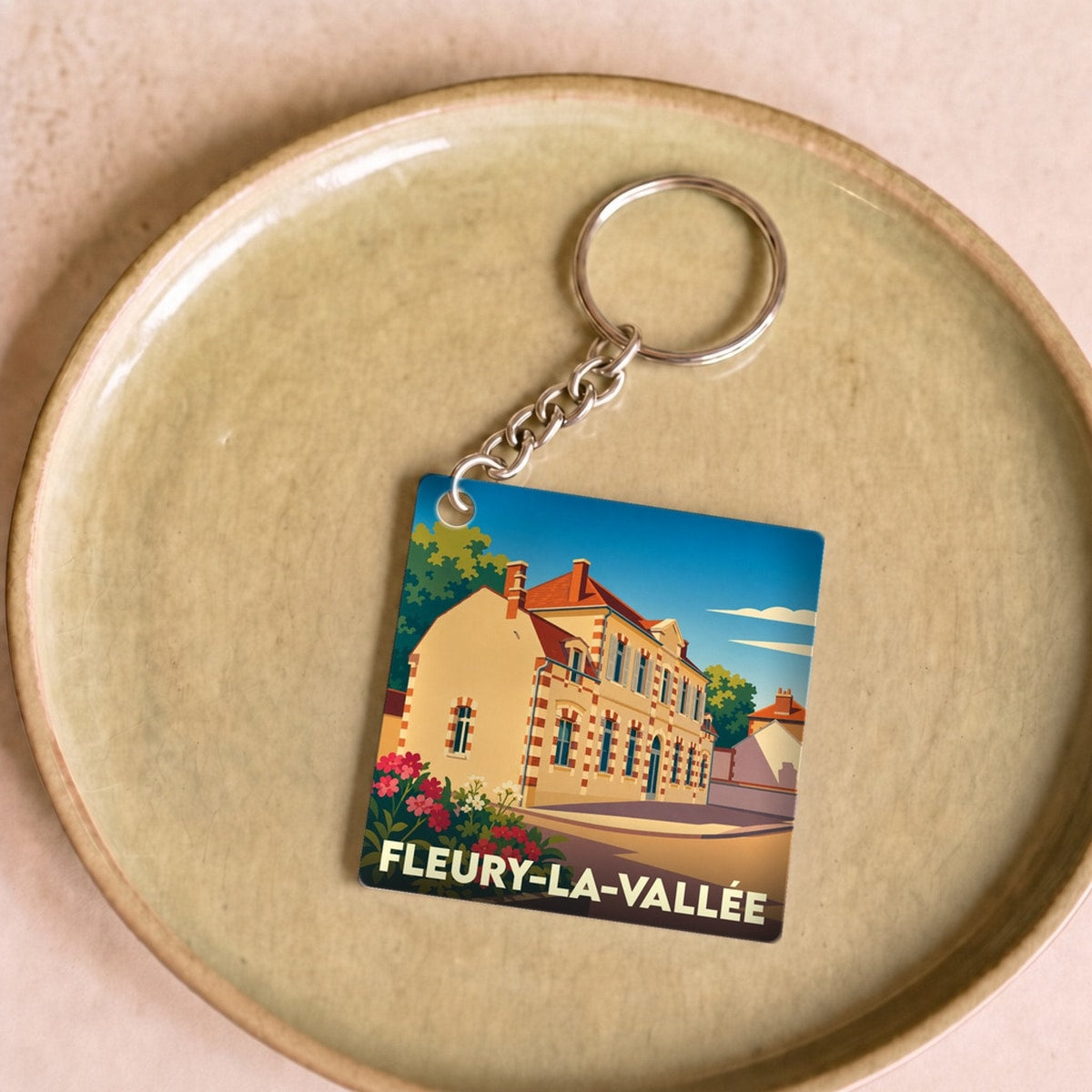 Porte-clés souvenir de la ville de Fleury-la-Vallée avec une illustration stylisée.