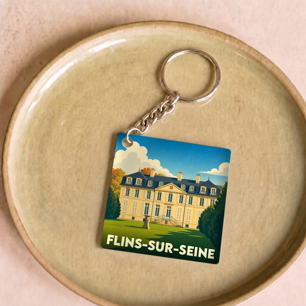 Porte-clés souvenir de la ville de Flins-sur-Seine avec une illustration stylisée d'un château.