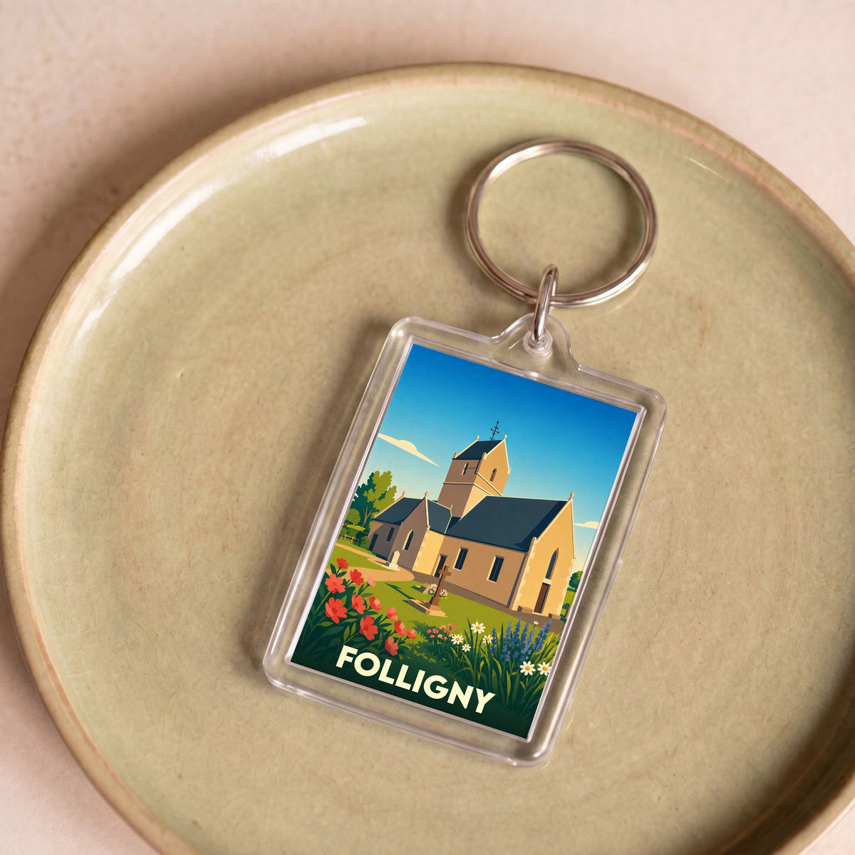 Porte-clés souvenir de la ville de Folligny avec une illustration stylisée de son église.