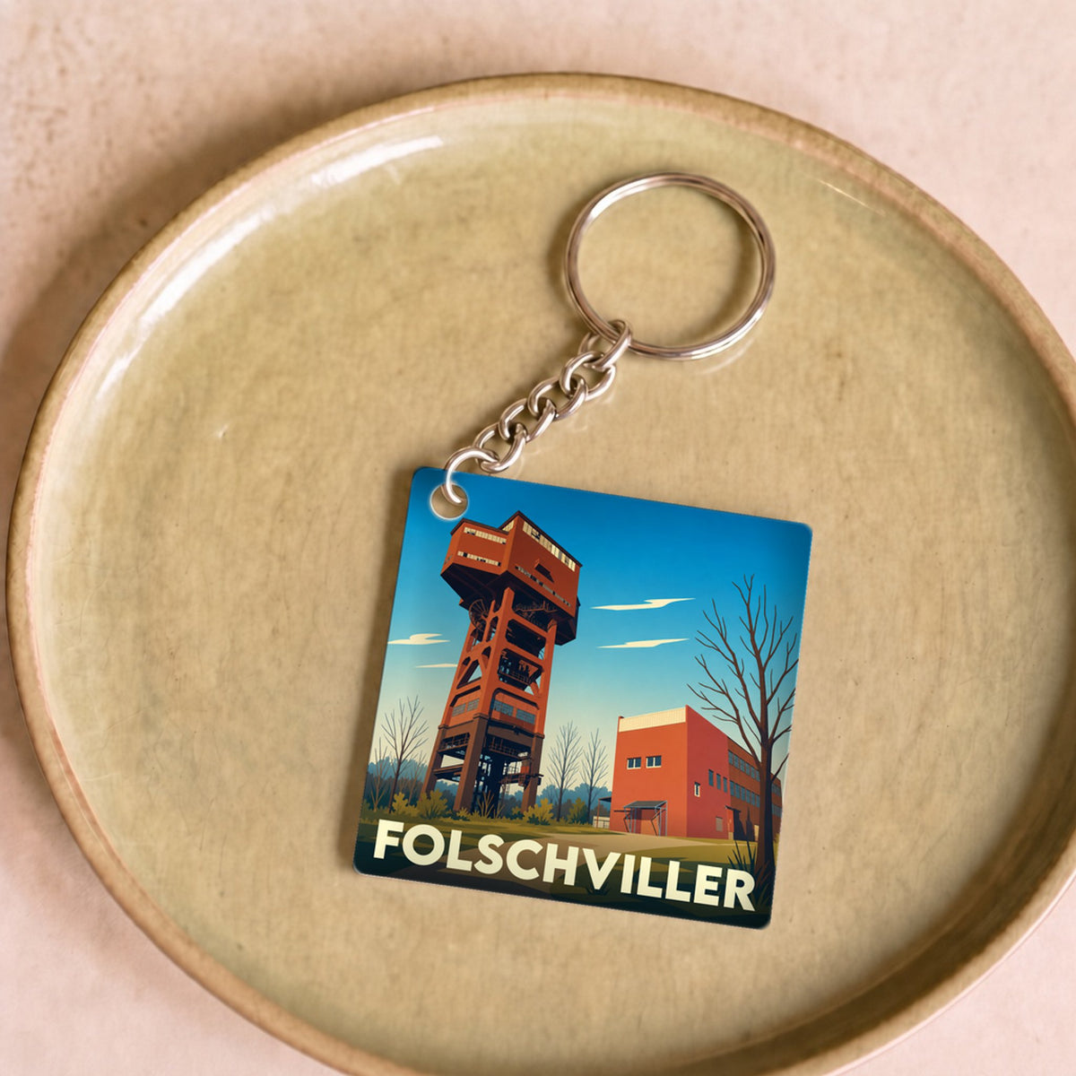 Porte-clés souvenir de la ville de Folschviller avec une illustration stylisée de son puits de mine.