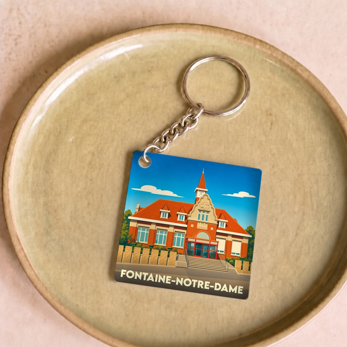 Porte-clés souvenir de la ville de Fontaine-Notre-Dame avec une illustration stylisée de son hôtel de ville.