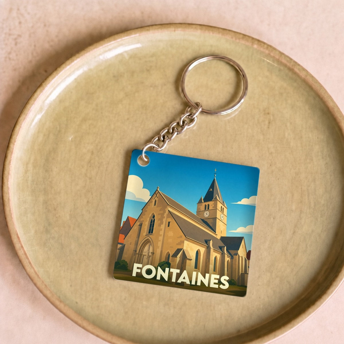 Porte-clés souvenir de la ville de Fontaines avec une illustration stylisée de son église.