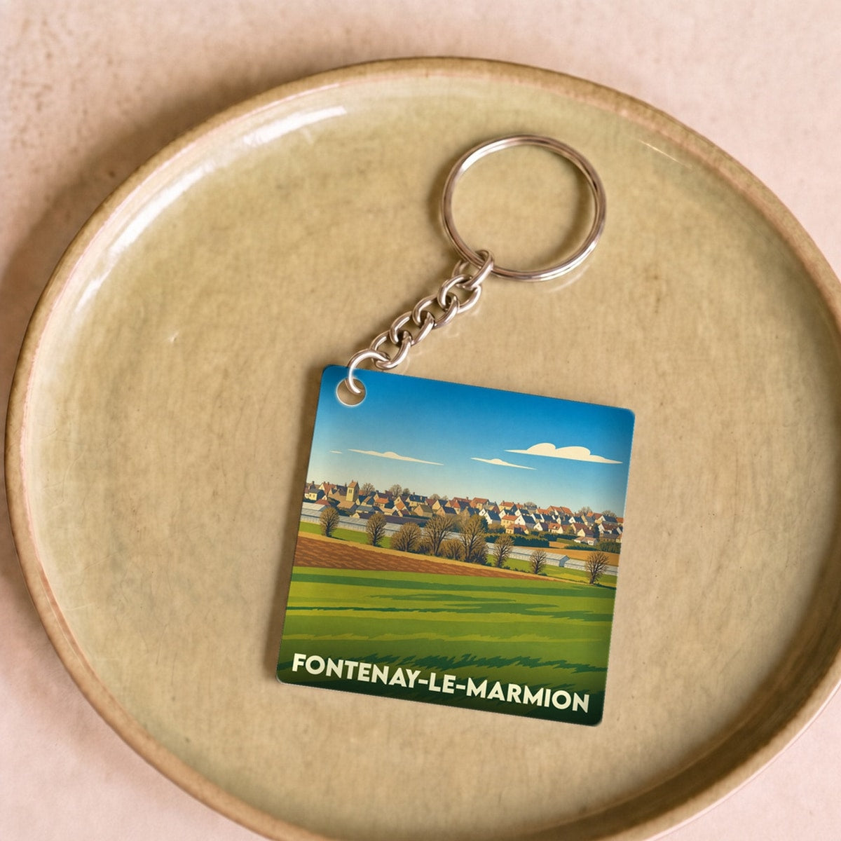 Porte-clés souvenir de la ville de Fontenay-le-Marmion avec une illustration stylisée d'un paysage rural.