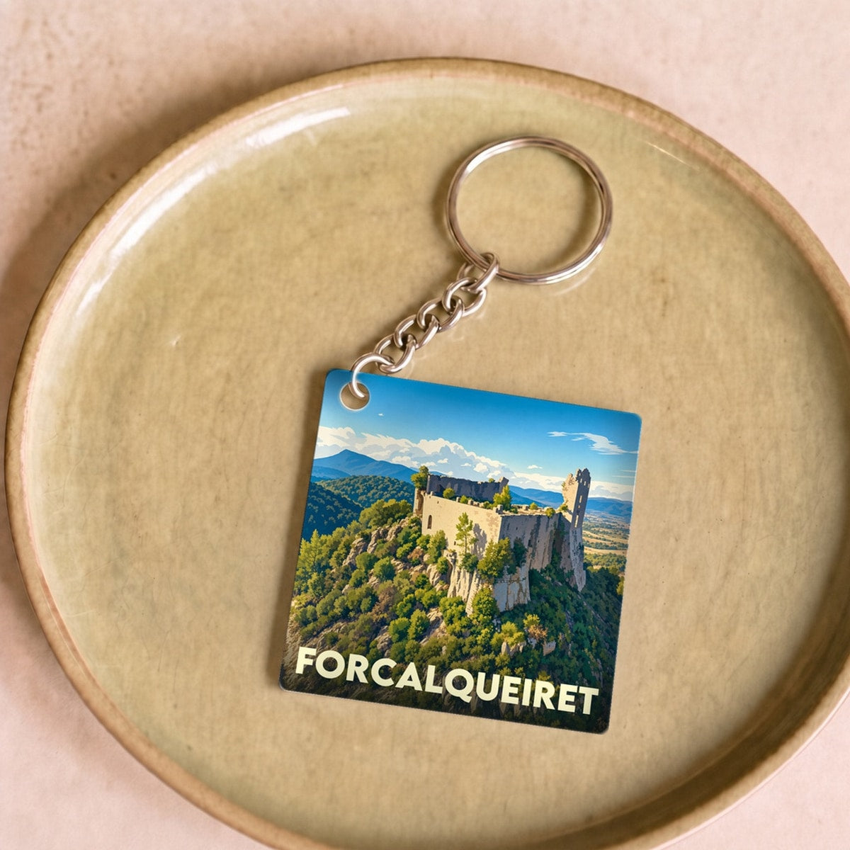 Porte-clés souvenir de la ville de Forcalqueiret avec une illustration stylisée du château sur sa colline.