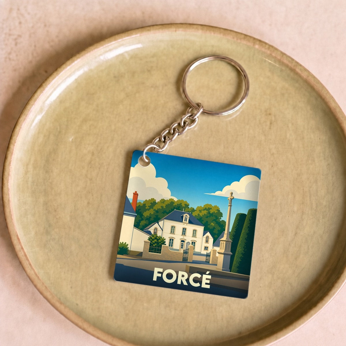 Porte-clés souvenir de la ville de Forcé avec une illustration stylisée.