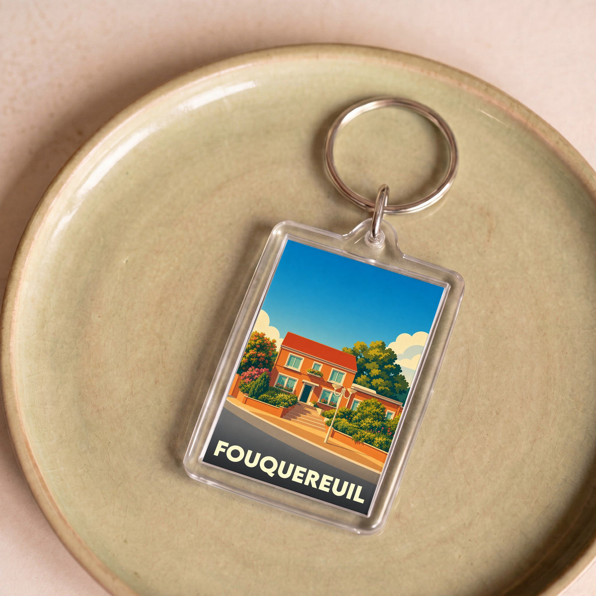 Porte-clés souvenir de la ville de Fouquereuil avec une illustration colorée et stylisée d'une maison.