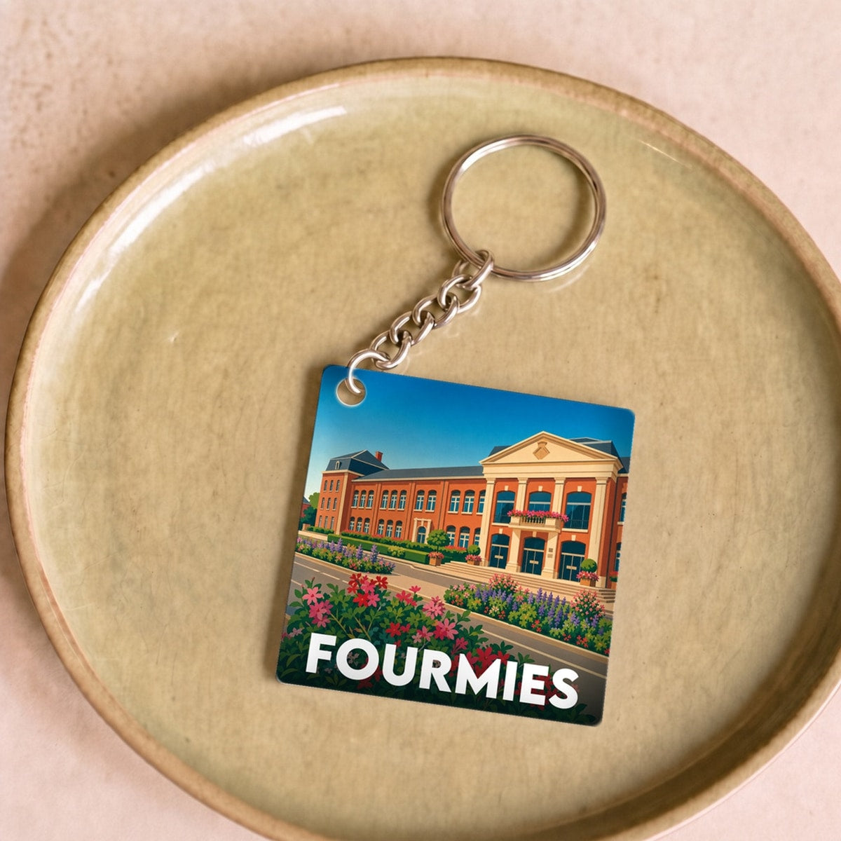Porte-clés souvenir de la ville de Fourmies avec une illustration stylisée.