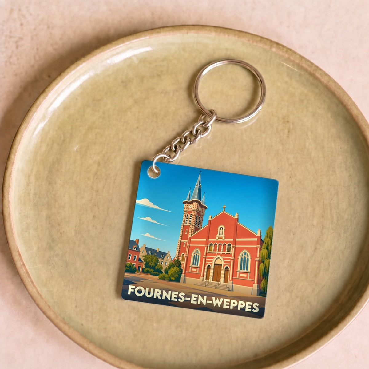 Porte-clés souvenir de la ville de Fournes-en-Weppes avec une illustration stylisée de son église.