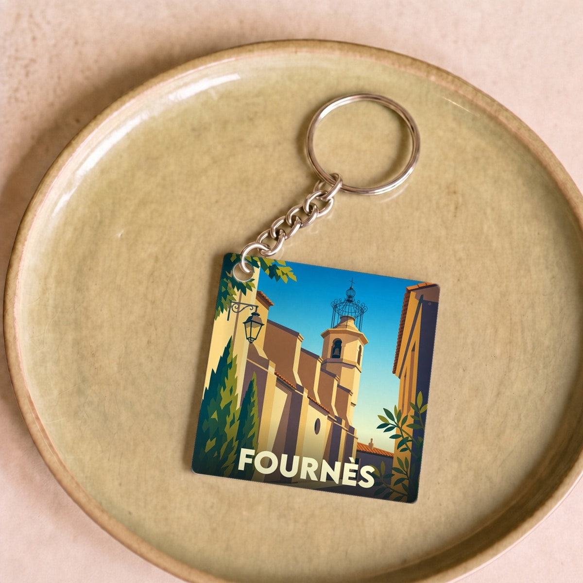 Porte-clés souvenir de la ville de Fournès avec une illustration stylisée.