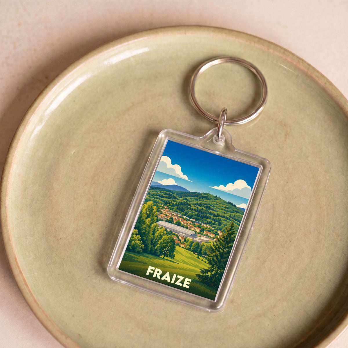 Porte-clés souvenir de la ville de Fraize avec une illustration stylisée d'un paysage montagneux.