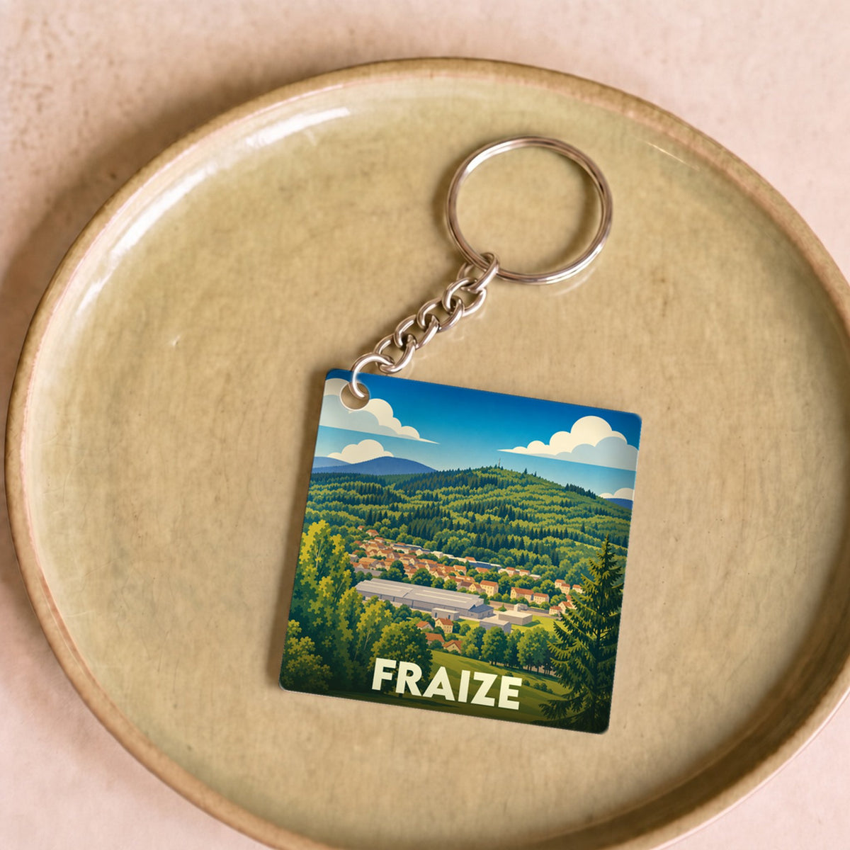 Porte-clés souvenir de la ville de Fraize avec une illustration stylisée d'un paysage montagneux.