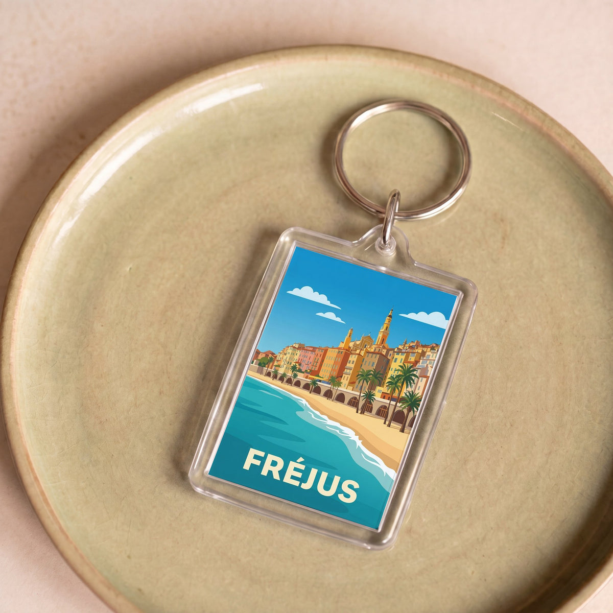 Porte-clés souvenir de la ville de Fréjus avec une illustration stylisée du front de mer.