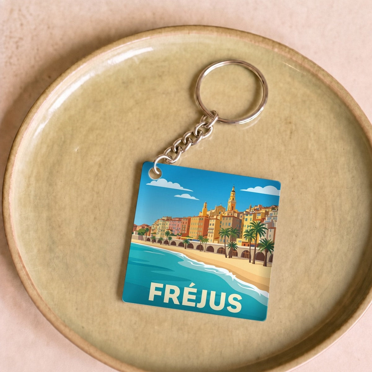 Porte-clés souvenir de la ville de Fréjus avec une illustration stylisée du front de mer.