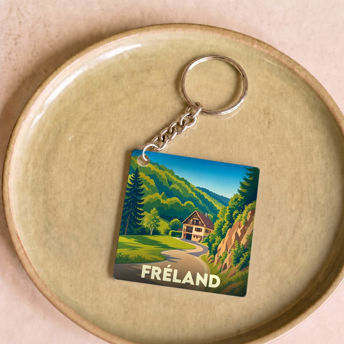 Porte-clés souvenir de la ville de Fréland avec une illustration stylisée d'un paysage de montagne.