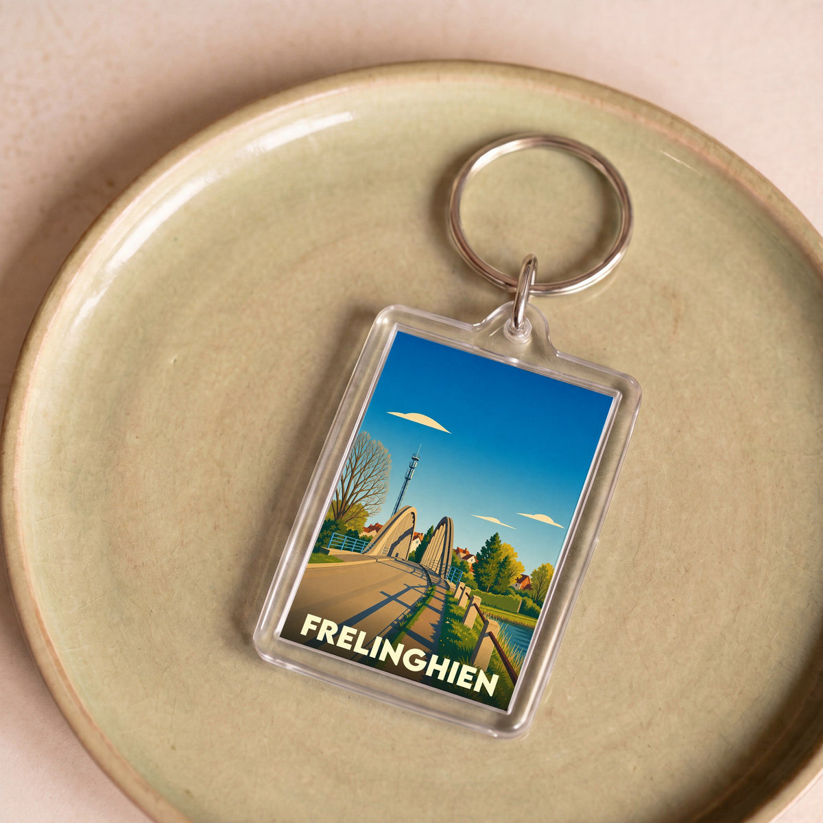 Porte-clés souvenir de la ville de Frelinghien avec une illustration stylisée de son pont et de son clocher.