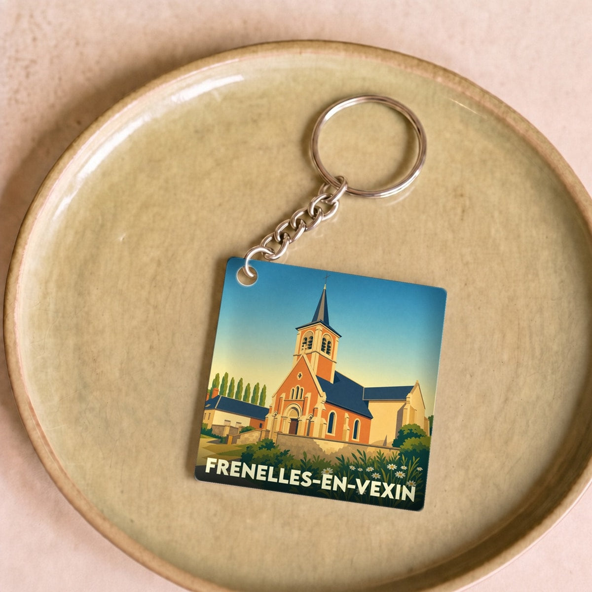 Porte-clés souvenir de la ville de Frenelles-en-Vexin avec une illustration stylisée de son église.