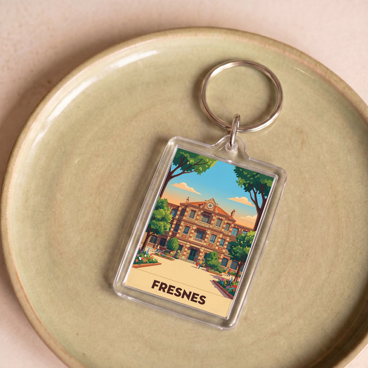 Porte-clés souvenir de la ville de Fresnes avec une illustration stylisée d'un bâtiment.