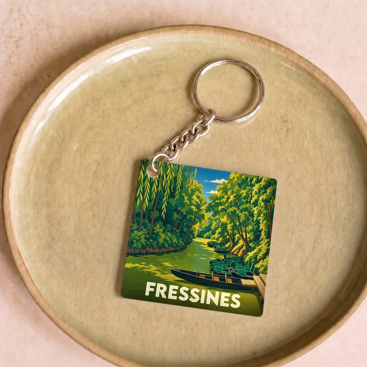Porte-clés souvenir de la ville de Fressines avec une illustration stylisée d'un canal boisé.