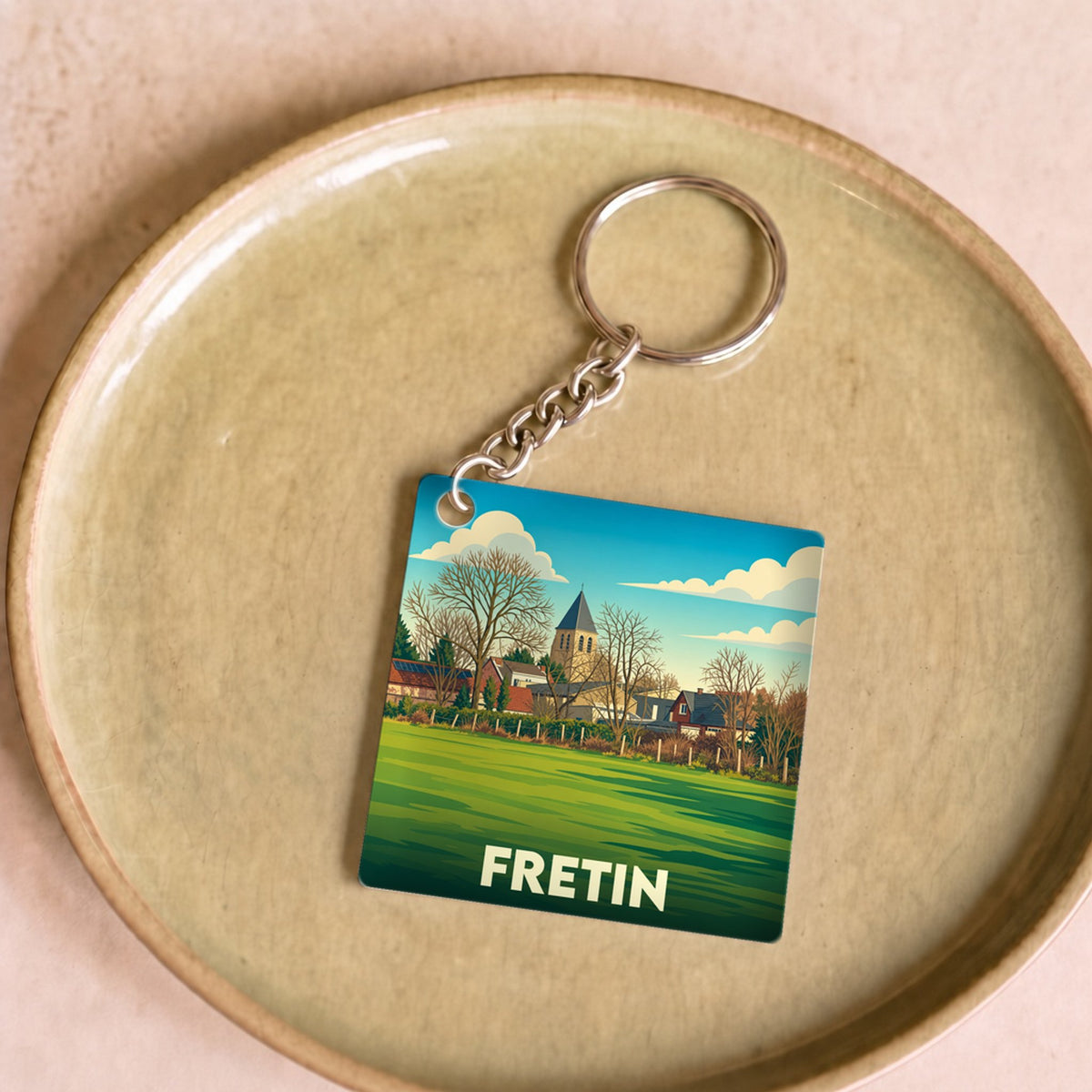 Porte-clés souvenir de la ville de Fretin avec une illustration stylisée.