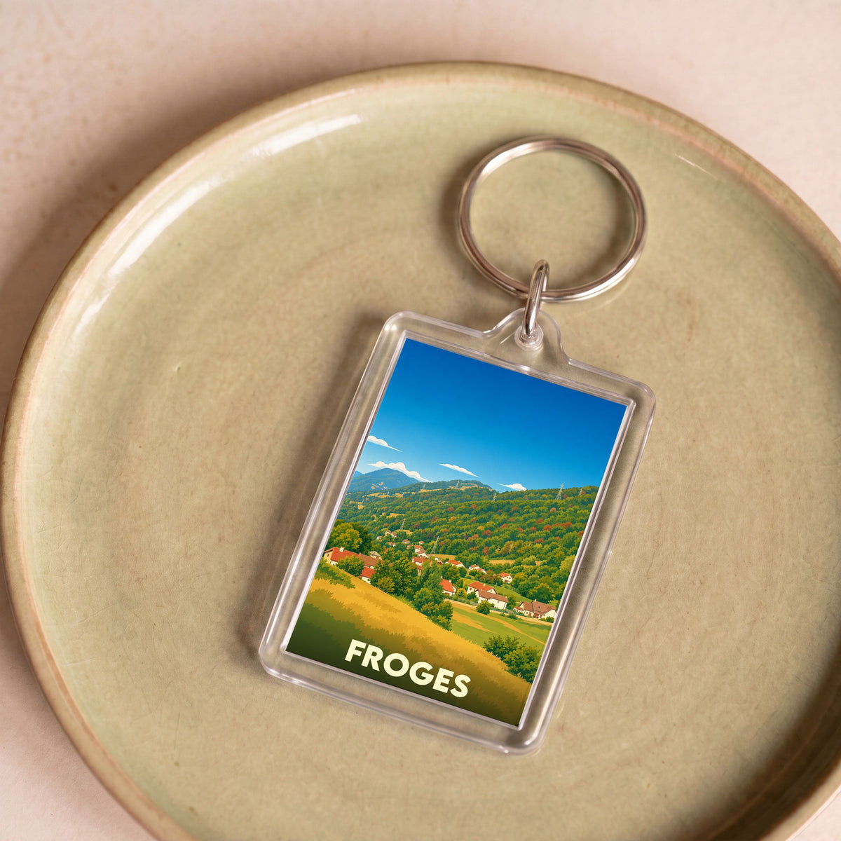 Porte-clés souvenir de la ville de Froges avec une illustration stylisée d'un paysage montagneux.