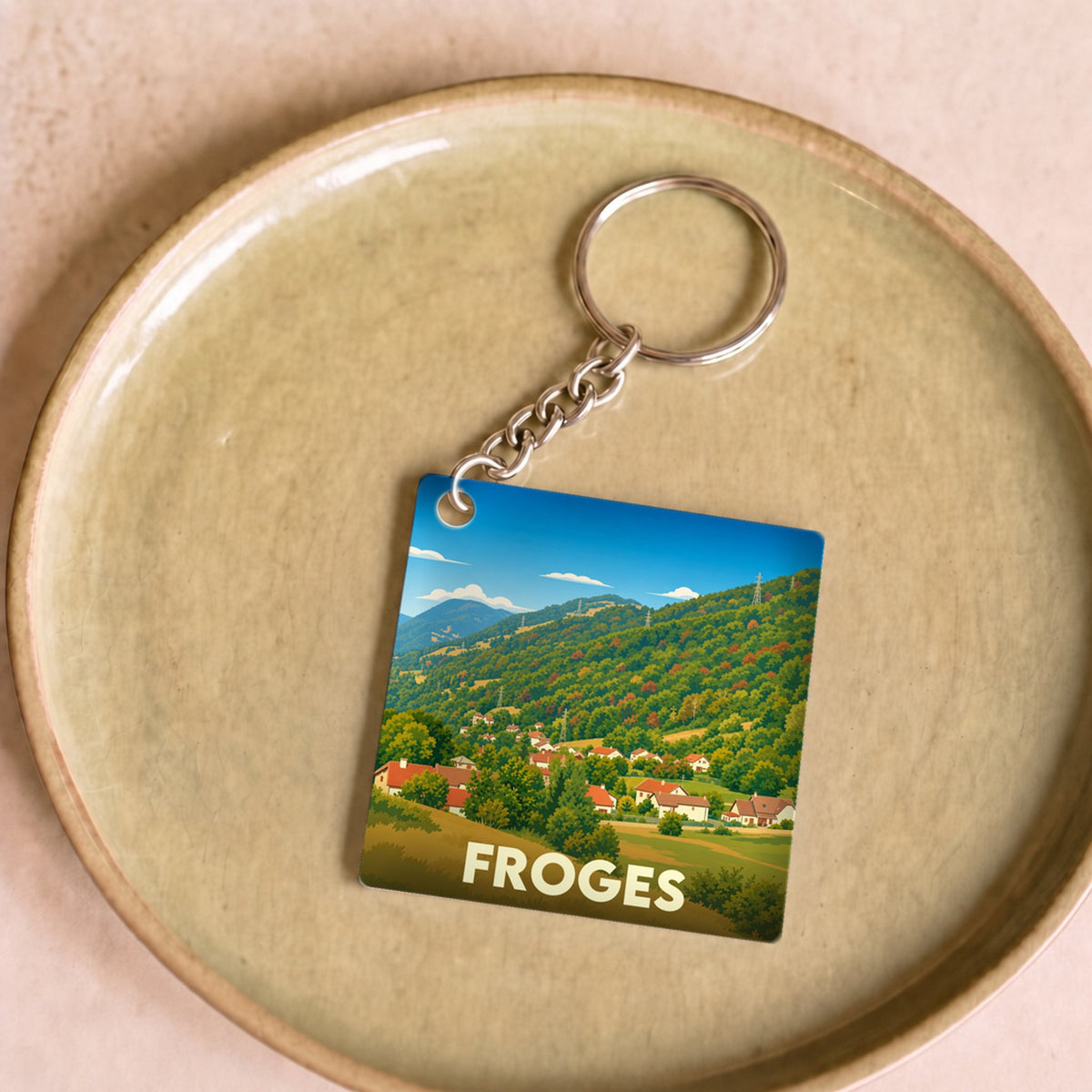 Porte-clés souvenir de la ville de Froges avec une illustration stylisée d'un paysage montagneux.