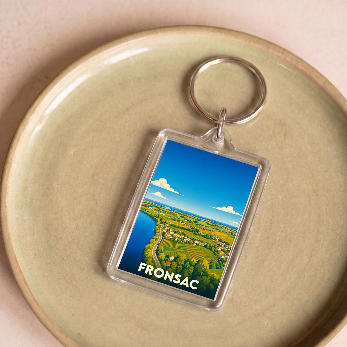 Porte-clés souvenir de la ville de Fronsac avec une illustration paysagère stylisée.
